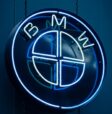 Illuminated blue neon BMW logo sign photographed against a dark backdrop in İzmir, Türkiye.